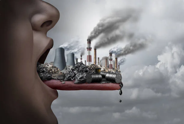 Conceptual illustration of a human mouth consuming industrial pollution and toxic waste.
